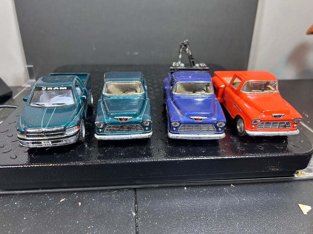 four diecast trucks, gRAM pickup, classic Chevrolet Stepside trucks, tow truck.